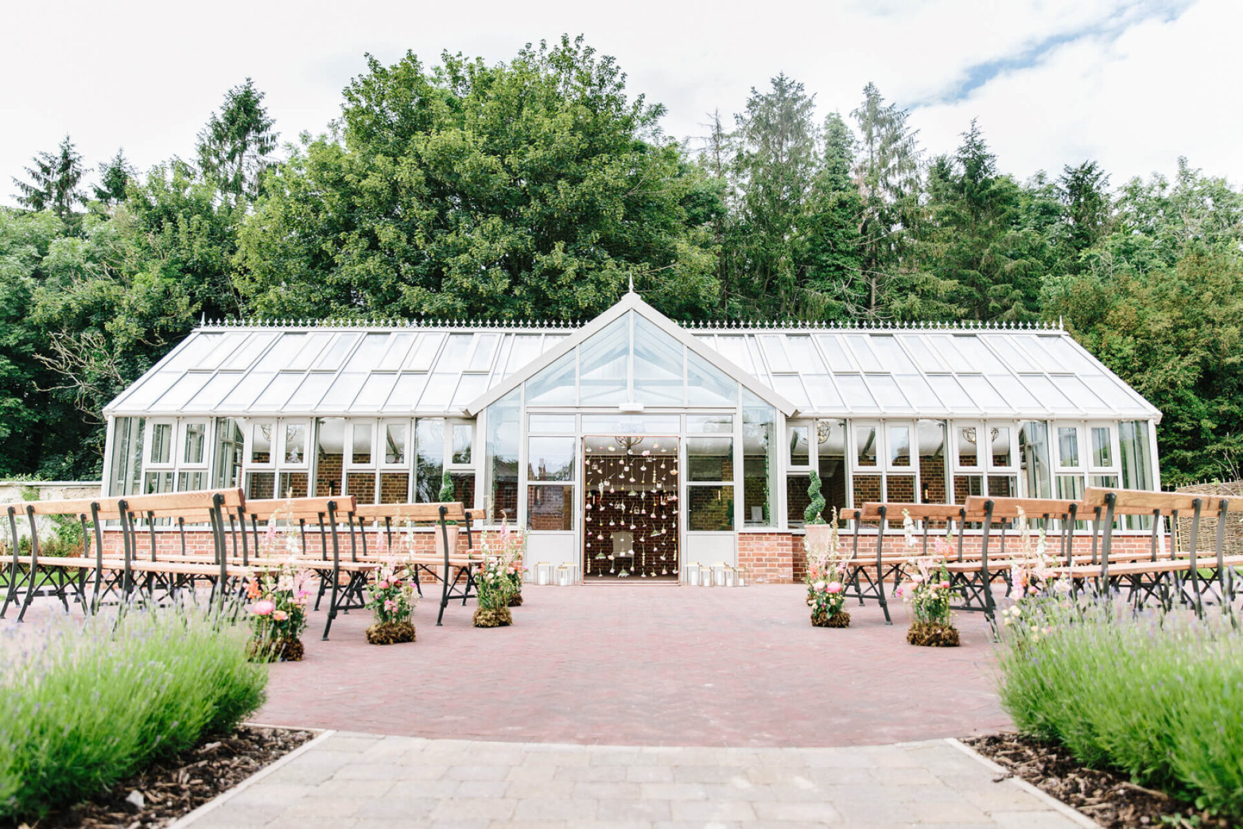 Stylish greenhouse wedding venue surrounded by lush greenery, featuring outdoor seating and charming floral accents. Ideal for intimate ceremonies.