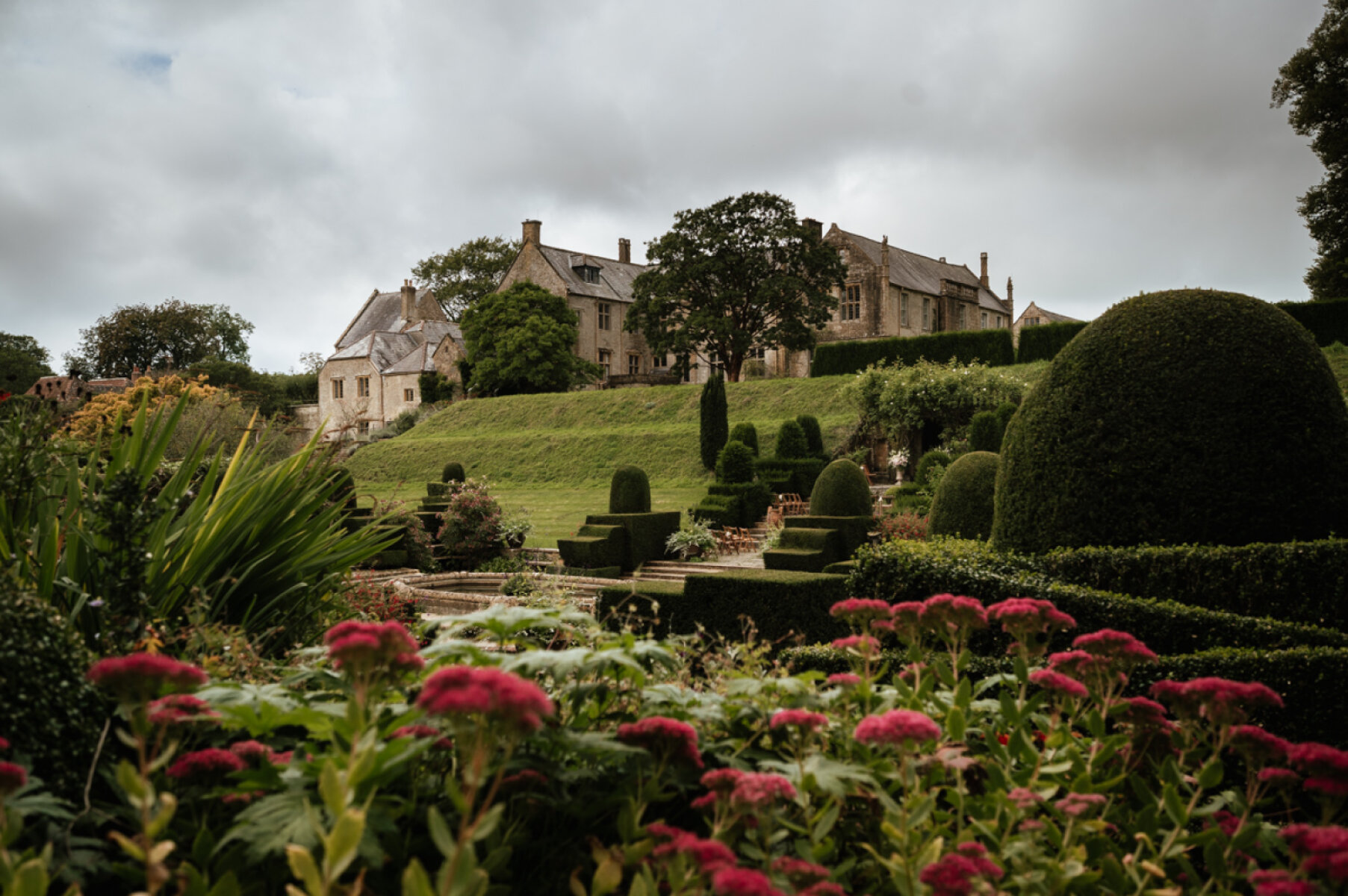 Lush gardens filled with vibrant flowers surround a charming estate, offering a serene backdrop for outdoor ceremonies and intimate gatherings.