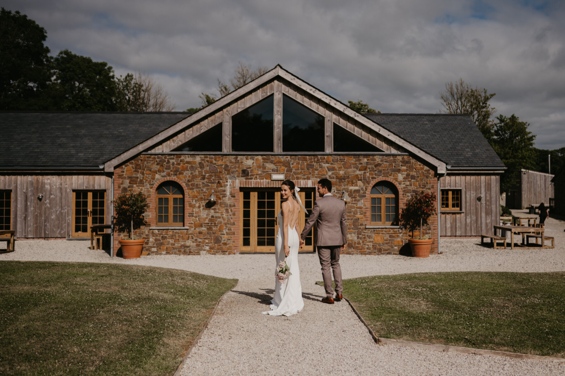 Charming rustic barn venue with stone exterior, large windows, and well-kept grounds, perfect for outdoor ceremonies and intimate gatherings.