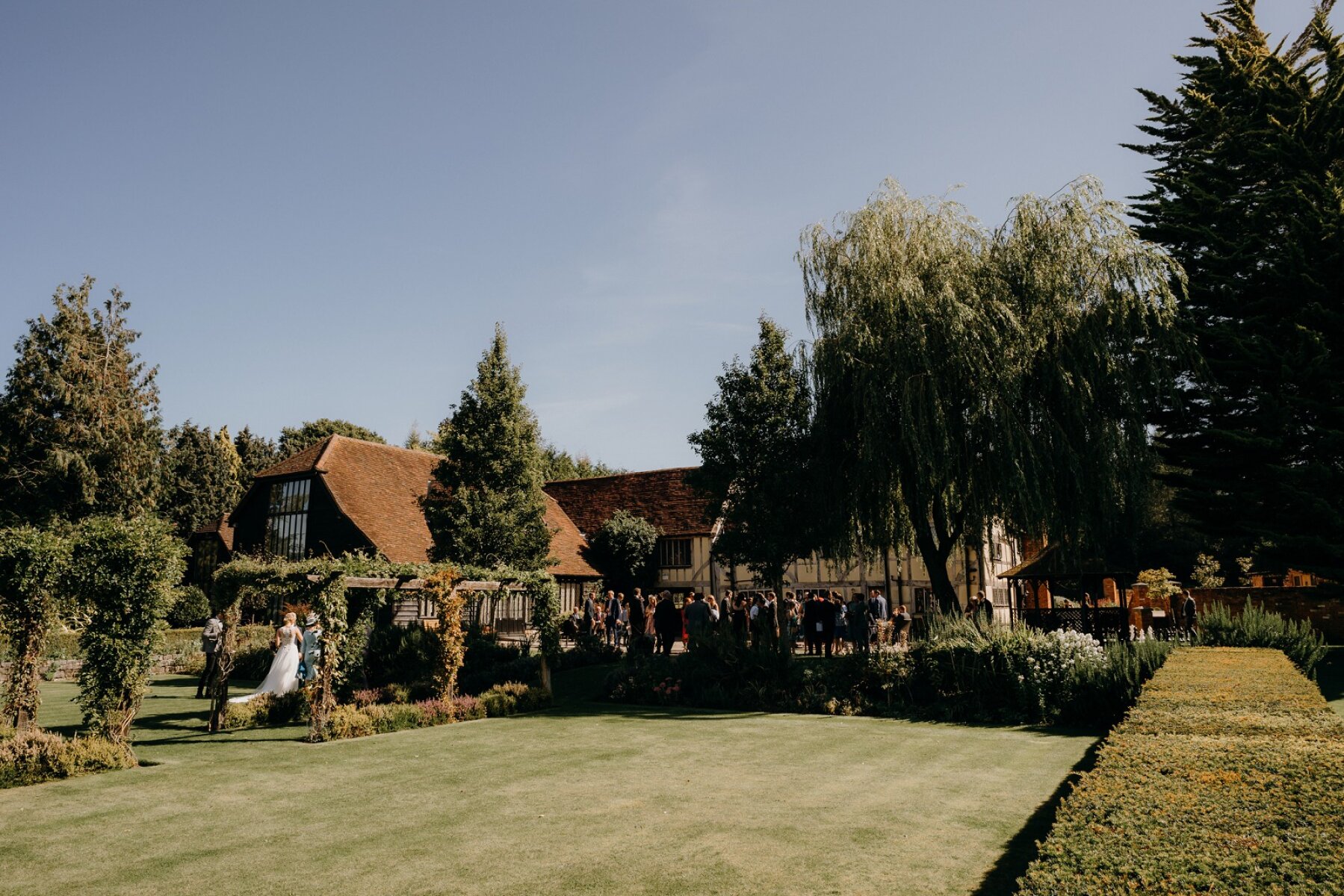 Lush outdoor ceremony space featuring manicured lawns, vibrant greenery, and charming rustic buildings perfect for a romantic wedding.