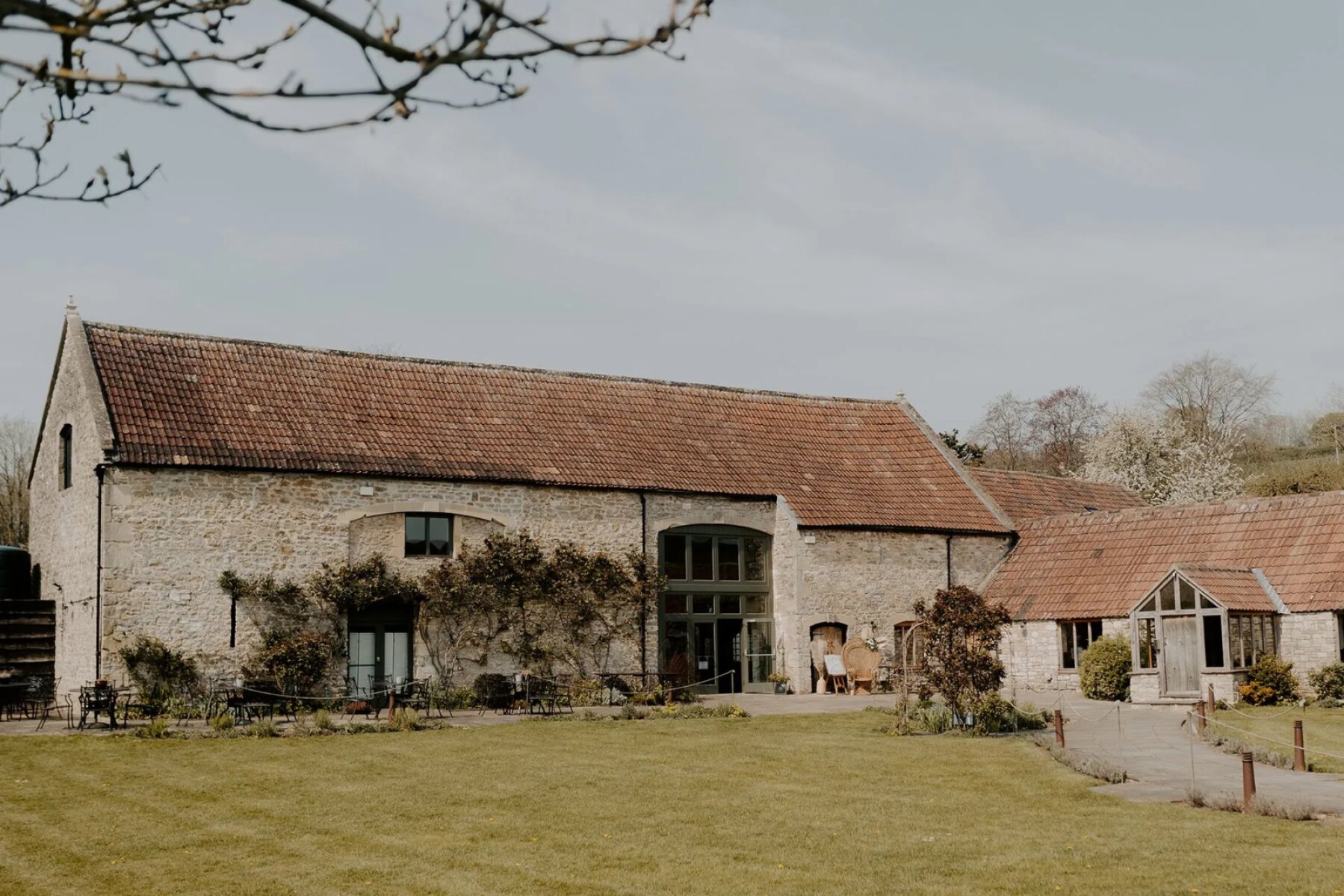 Charming rustic barn venue with stone exterior, lush green lawn, and beautiful garden for inviting outdoor ceremonies and celebrations.