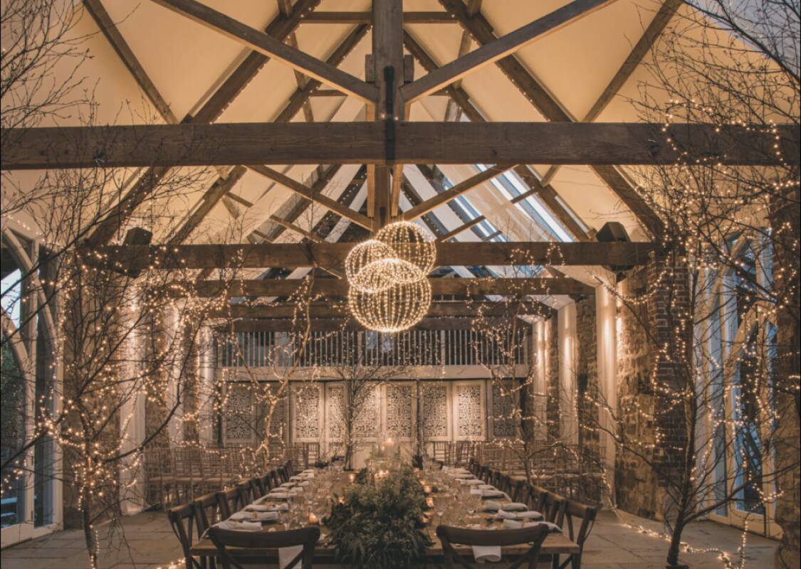 Charming rustic barn with wooden beams, elegant chandeliers, and fairy lights, perfect for intimate wedding receptions.
